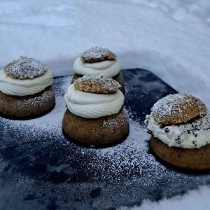 Neljä erilaista laskiaispullaa lumihankeen asetetun kivitason päällä